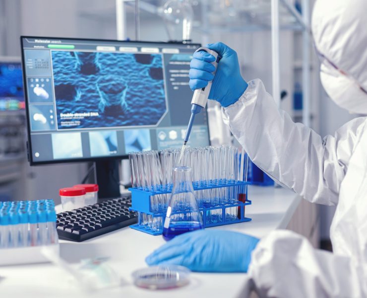 Virolog coducting experiment in the course of coronavirus pandemic with micropipette. Chemist in modern laboratory doing research using dispenser during global epidemic with covid-19.